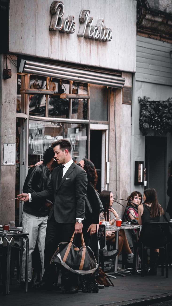 man in a suit with a sports bag standing in a city street
