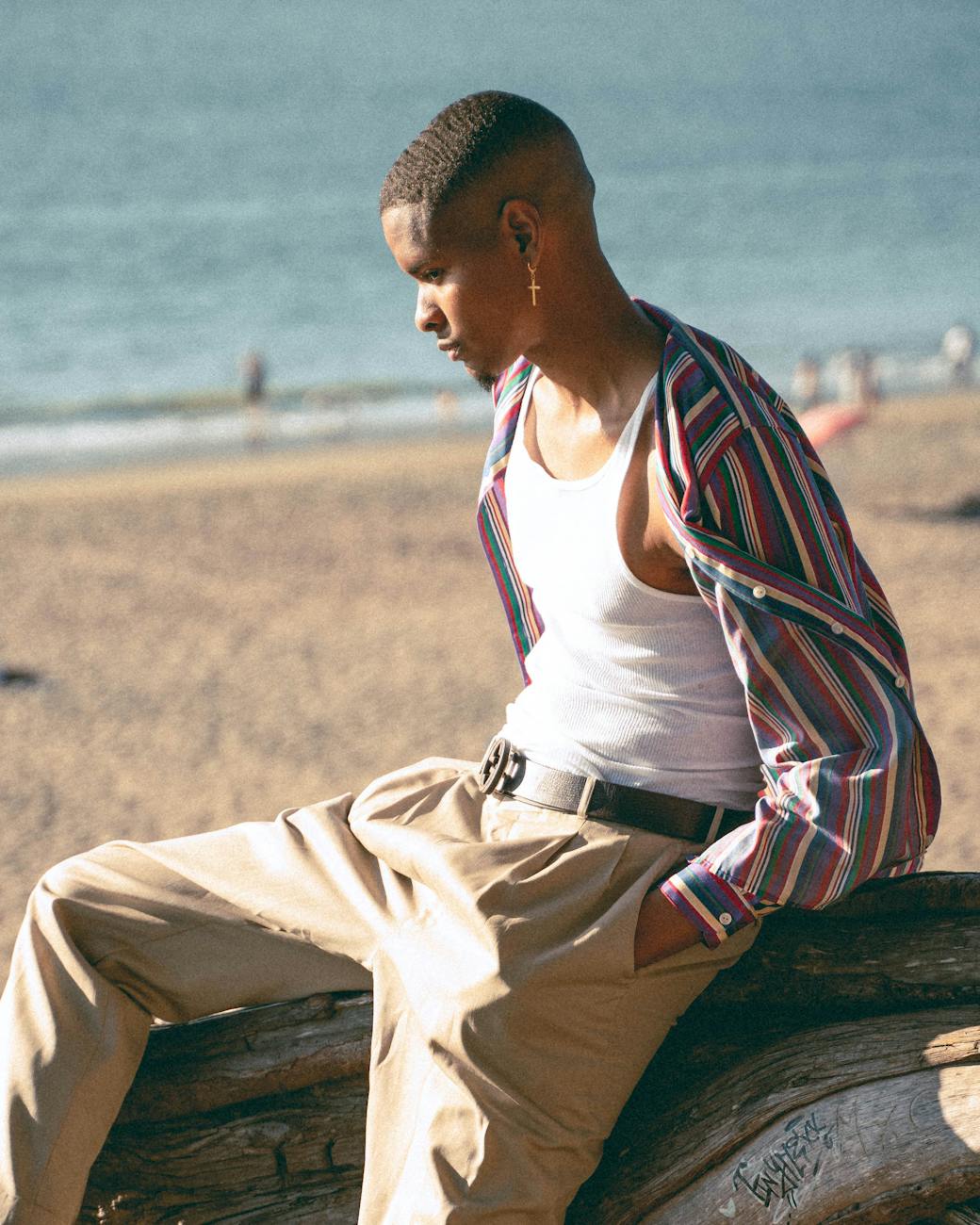 a man sitting on a tree trunk by the beach