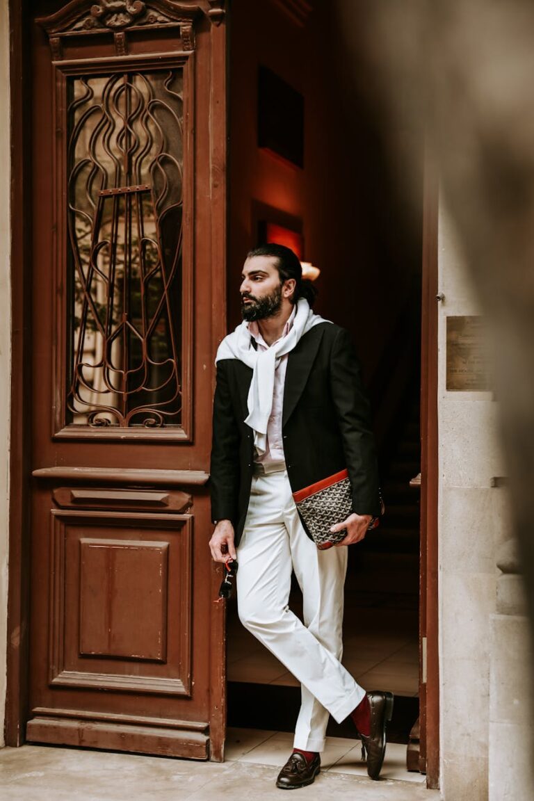 stylish man leaning on doorway with clutch bag