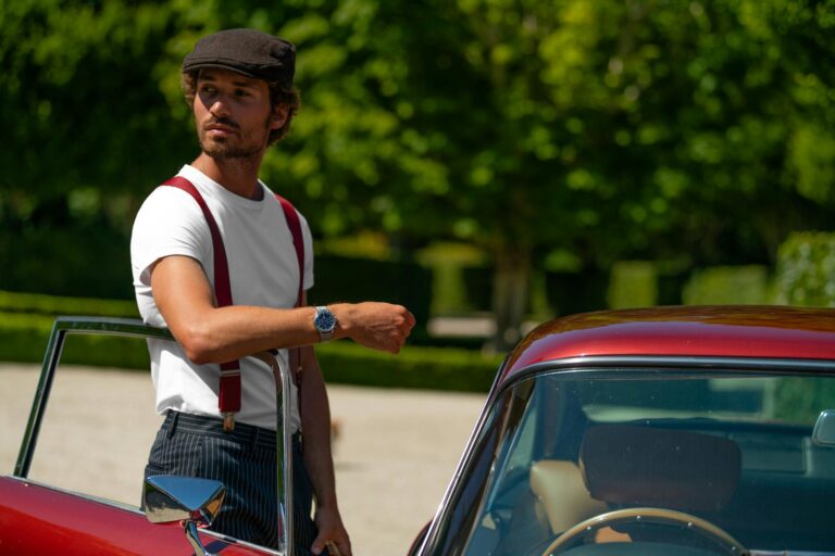man in white crew neck t shirt standing beside red car